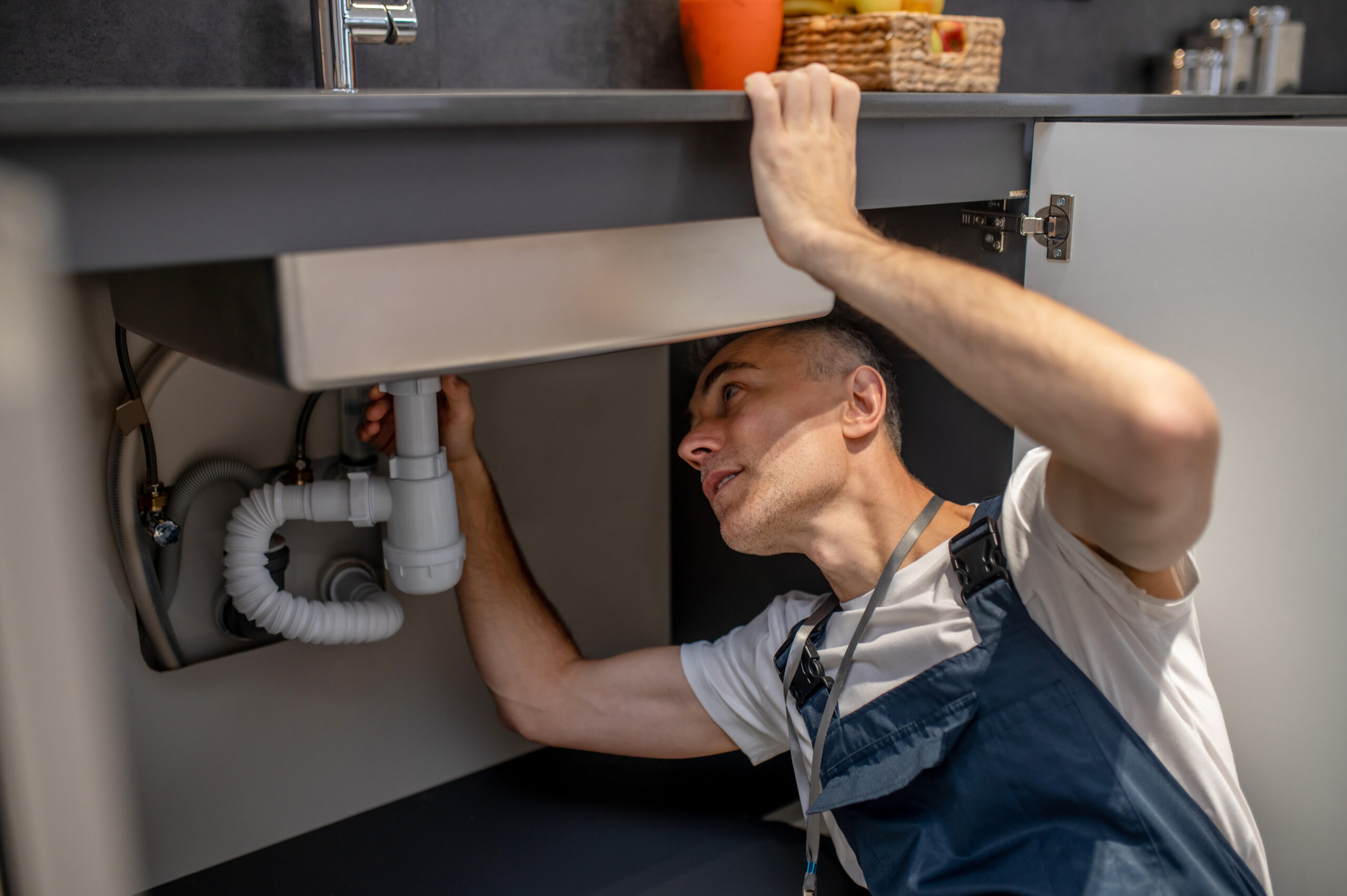 Man carefully examining bottom of sink and pipe Heinert Plumbing and Drain LLC|Heinert Plumbing: Drain Cleaning Services in Easley, SC